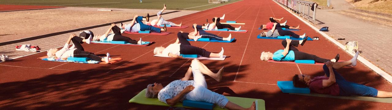 Eine Gruppe von Sporttreibenden auf dem Sportplatz mit Sicherheitsabstand.