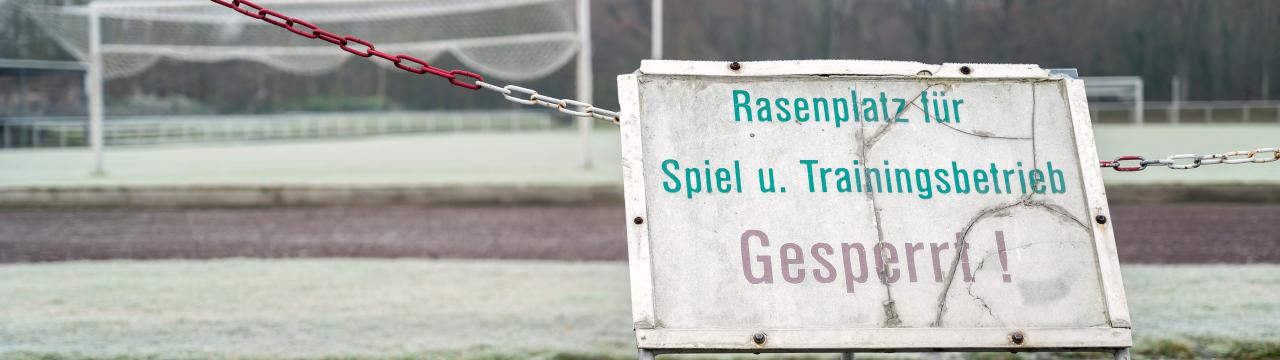 Rasengesperrt-Schild vor Sportplatz.