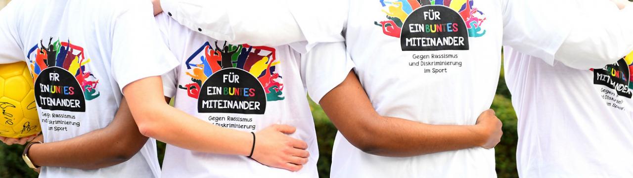 Junge Sportler (von hinten) stehen umarmend nebeneinander