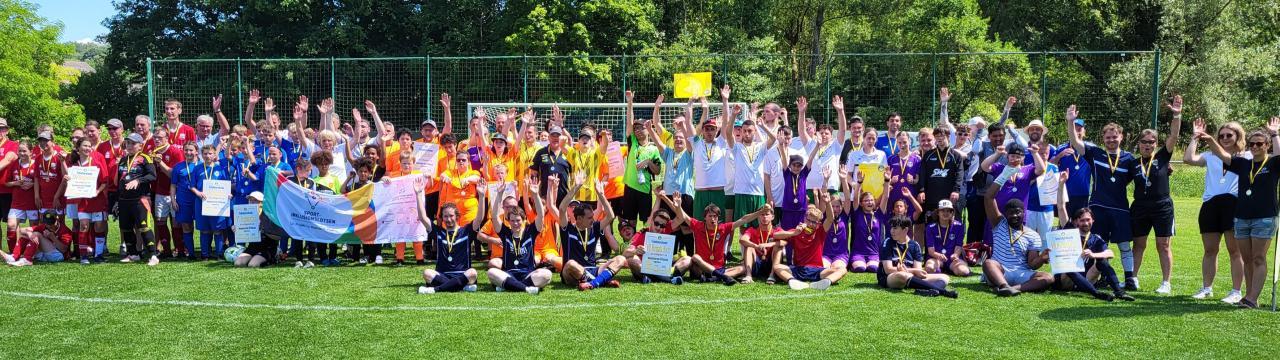 Gruppenfoto mit vielen Sportler*innen auf einem Fußballplatz