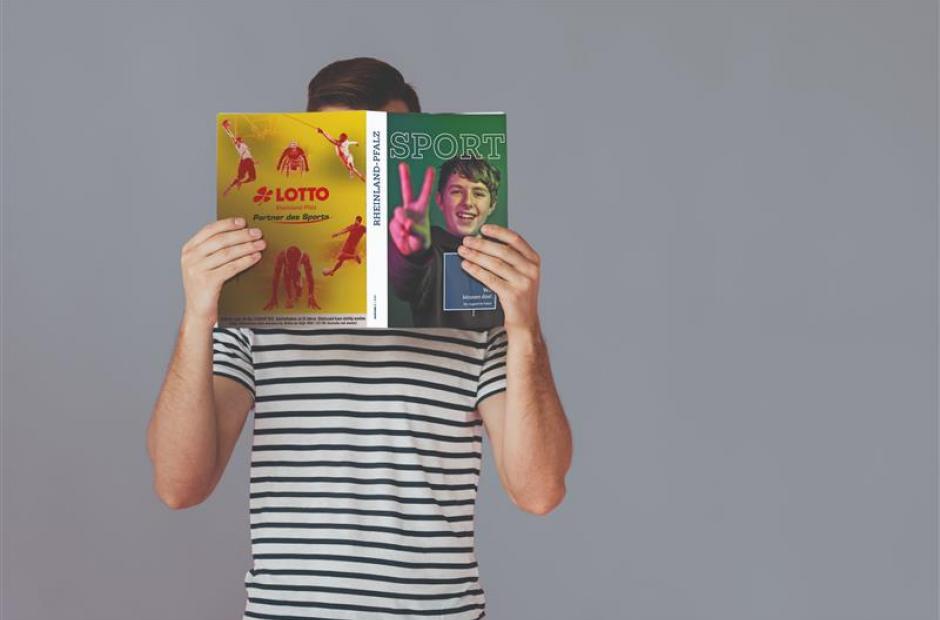Person, die Magazin vor dem Gesicht hält und liest