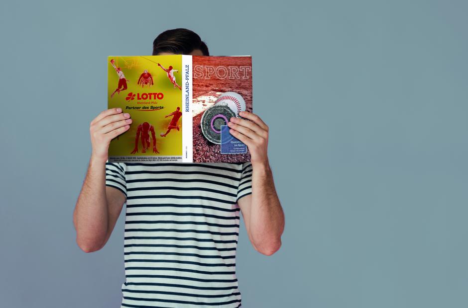 Person, die Magazin vor dem Gesicht hält und liest