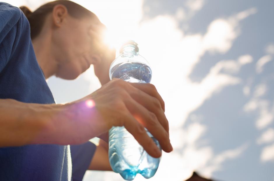 Frau, die bei großer Hitze eine Wasserflasche in der Hand hält
