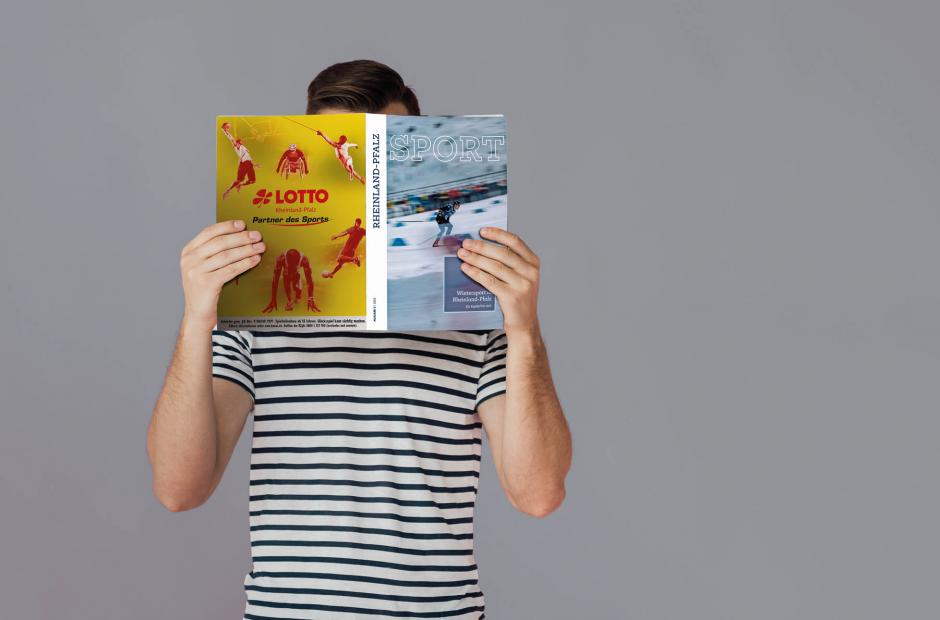 Eine Person, die ein Magazin vor ihr Gesicht hält