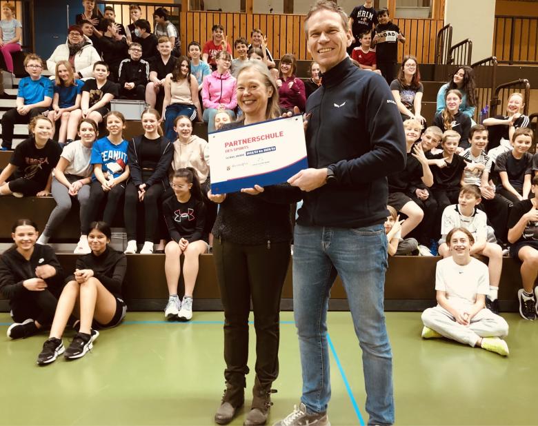 Zwei Menschen in Sporthalle mit Urkunde