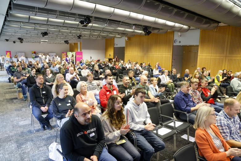 Ein mit auf Stühlen sitzenden Menschen gefüllter Raum