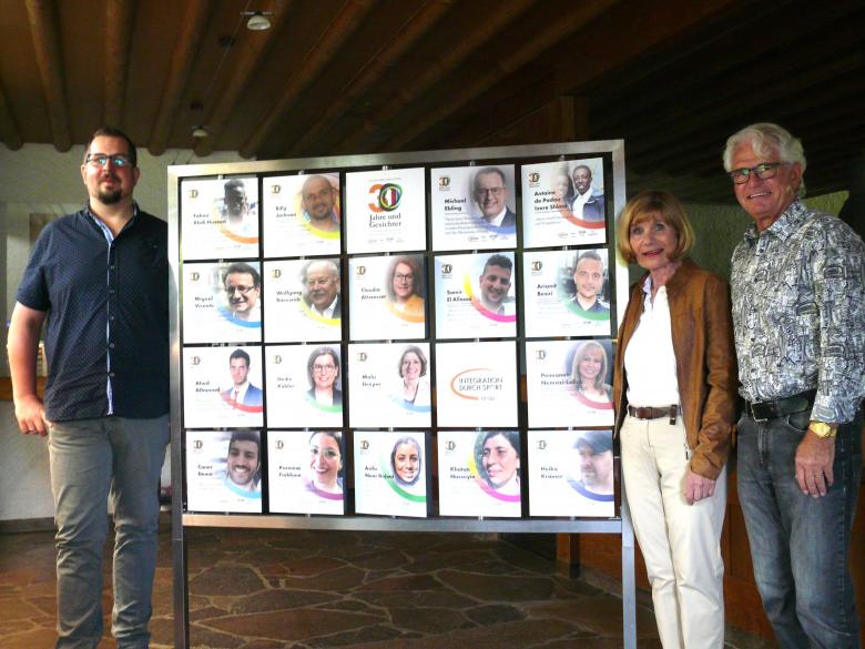 Drei Personen, die neben eine Ausstellung stehen