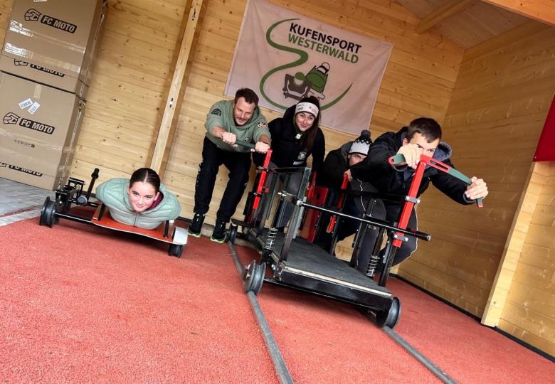 5 Sportler*innen, die den Anschub eines Bobs simulieren
