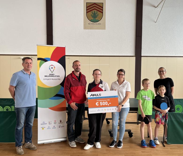 Personen in Sporthalle bei Scheckübergabe