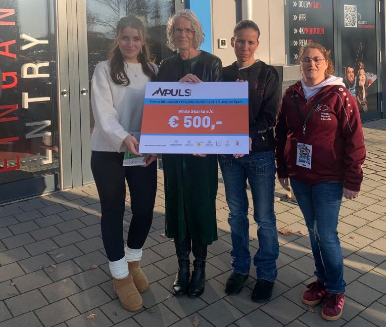 Vier Personen bei Scheckübergabe