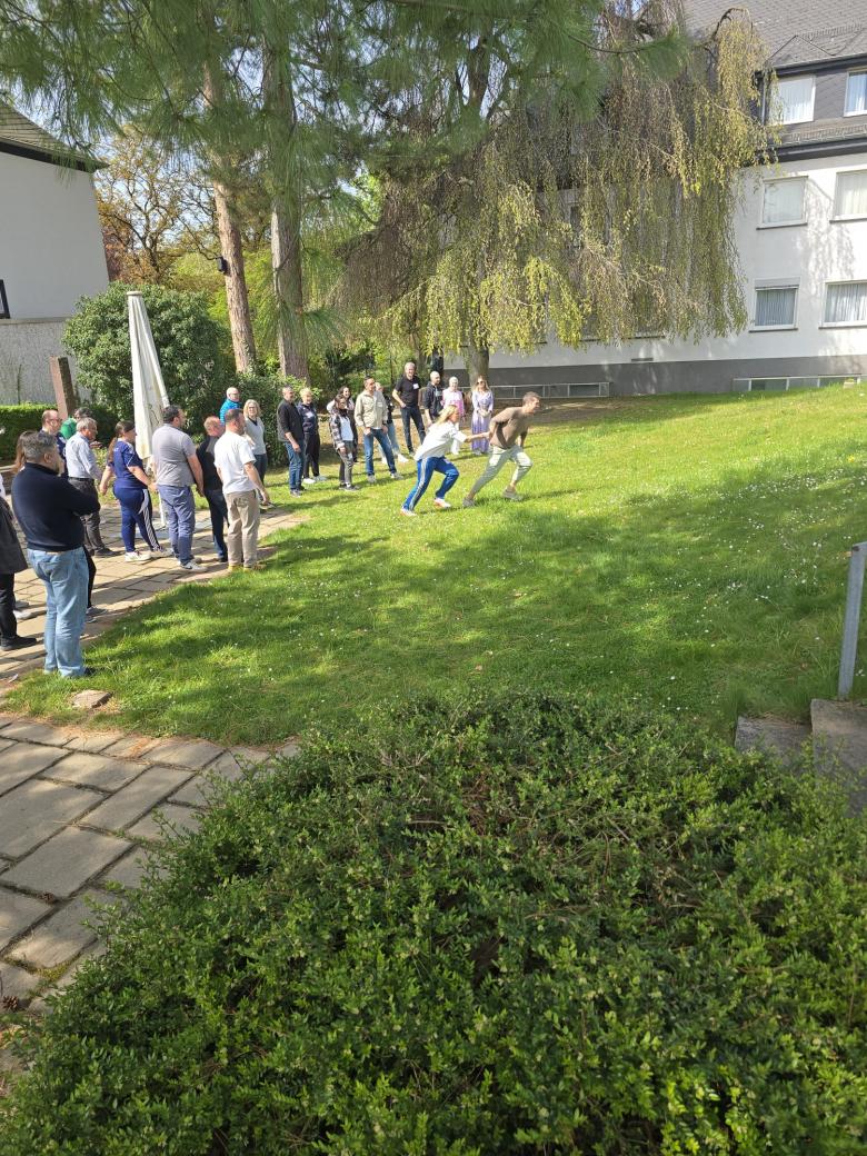 Das Foto zeigt den Programmleiter Christian Bürkel, wie er im Rahmen der praktischen Übung versucht, möglichst viele der untenstehenden Teilnehmer*innen zu sich "hoch" zu holen.