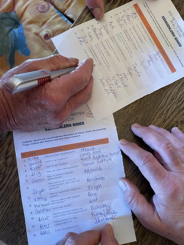 Zwei Personen haben ihre Bingo-Kennenlern-Karten vollständig ausgefüllt.