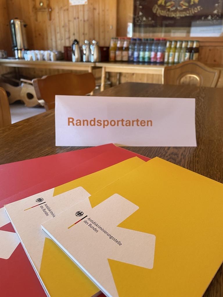 Das Foto zeigt einen "Thementisch". Auf dem Tisch steht ein Aufsteller mit der Aufschrift "Randsportarten". Davor liegen ein paar Notizblöcke der Antidiskriminierungsstelle des Bundes. 
