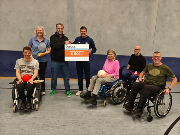 Scheckübergabe in Sporthalle mit Rollstuhlfahrern