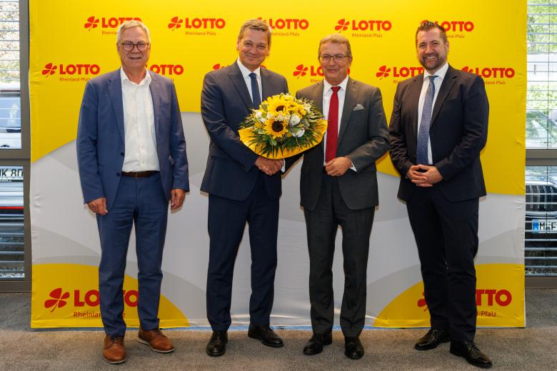 Vier Männer vor Lotto-Wand