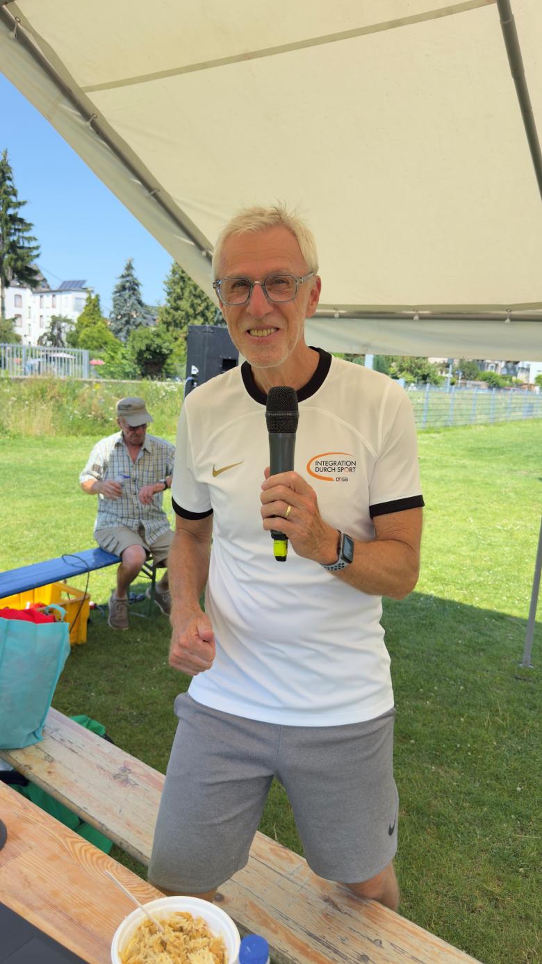 Das Foto zeigt den Programmreferenten "Integration durch Sport" Milan Kocian lachend und mit einem Mikrofon in der Hand.