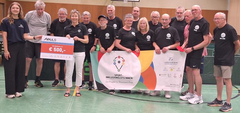 Viele Menschen bei Scheckübergabe in Sporthalle