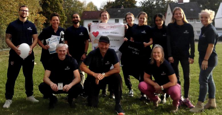 Sportliche Teilnehmer einer Fortbildung beim Gruppenfoto auf Rasen
