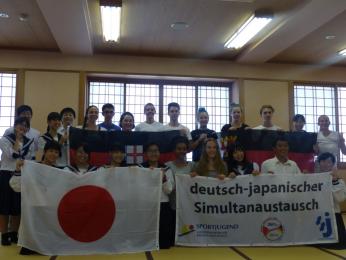 Deutsch-japanische Austauschgruppe beim Gruppenfoto mit japanischer Flagge.