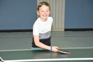 Junge lachend an Tischtennisplatte
