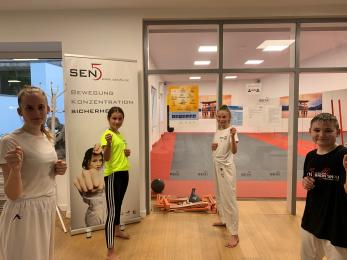 Trainingshalle des Sen5 Karate Verein e.V.mit einem LSB-Hygieneplakat und einem Teil unseres Nachwuchs-Wettkampfteams. Luisa Hellinger, Mia Mußweiler, Ili Hellen und Tim Niederelz.  Alle sind Mitglieder des Karate Landeskaders Rheinland Pfalz, Ili Hellen ist Mitglied des DKV-Bundeskaders und amtierende Deutsche Schülermeisterin.