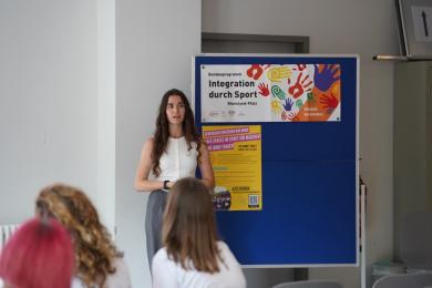 Eine Studentin stellt vor der Gruppe ein Mädchenprojekt vor.