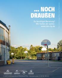 "...noch draußen" auf Foto mit Schulhof und blauem Himmel