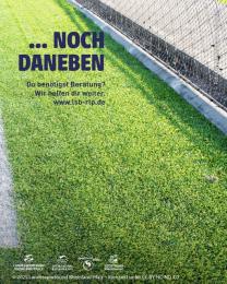 "...noch daneben" auf Foto eines Fußballrasens