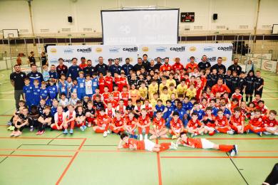 Gruppenfoto mit Beteiligten des Cage Soccer Turniers 2026. Zu sehen sind Spieler*innen, Trainer*innen und Helfer*innen.