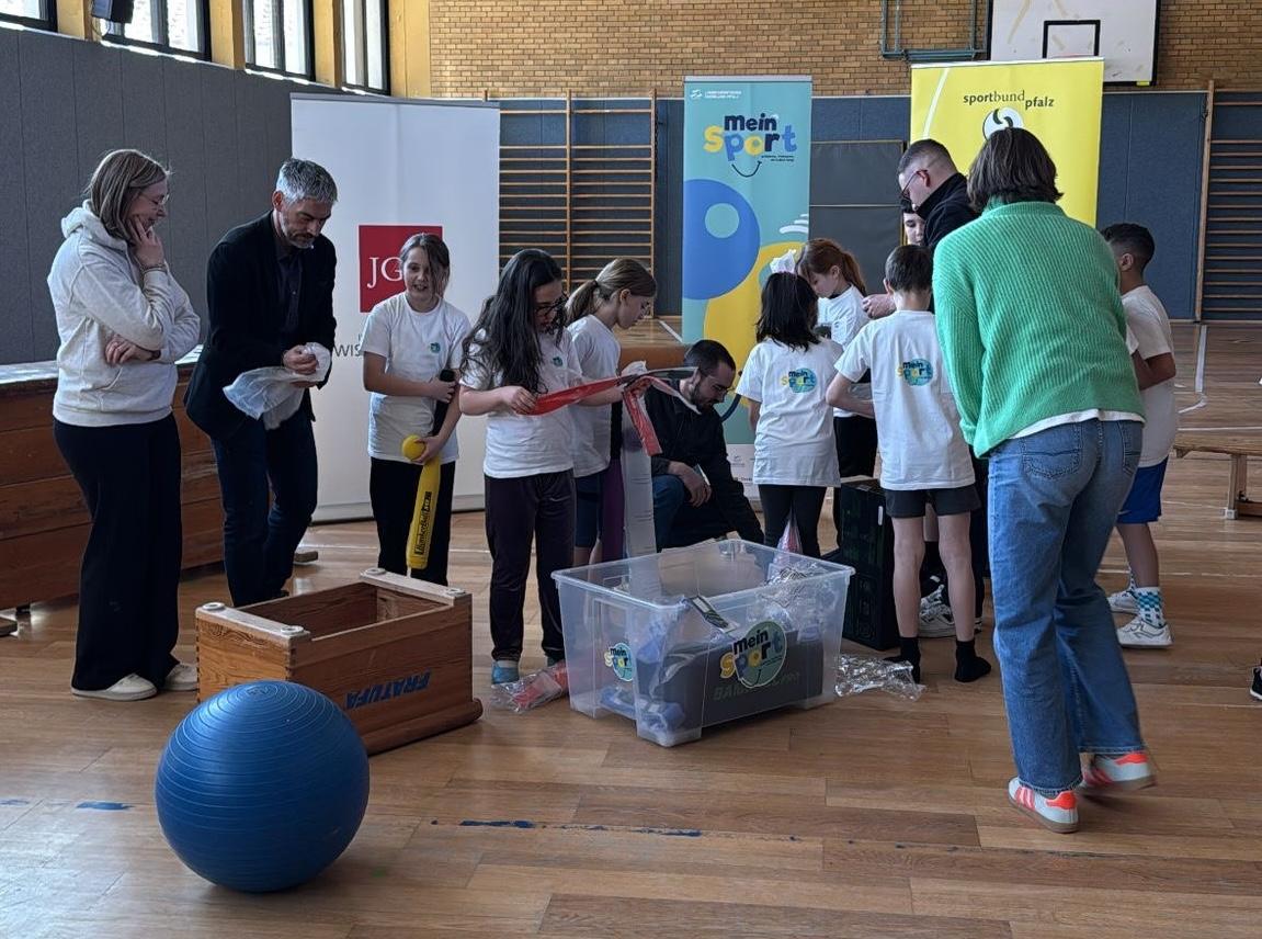 Kinder und Erwachsene stehen um eine Box mit Sportgeräten