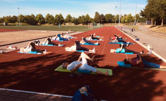Eine Gruppe von Sporttreibenden auf dem Sportplatz mit Sicherheitsabstand.