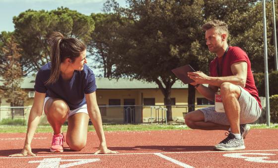 Ein Trainer spricht mit seiner Athletin auf einer Sportanlage