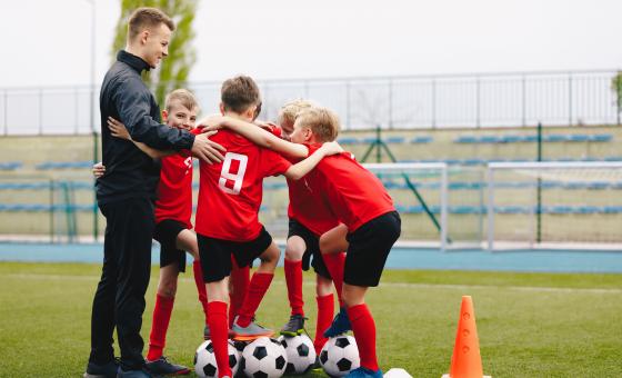 Junger Ehrenamtlicher im Sport mit Fußballmannschaft
