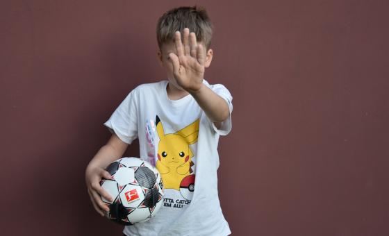 Kind mit Hand vor Gesicht