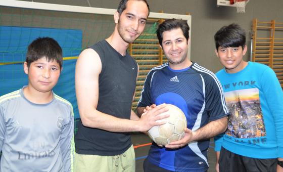 Flüchtlinge in Sporthalle mit Fußball