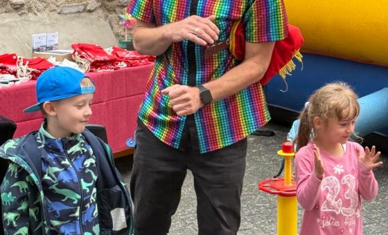 Ein Clown mit einem Hut aus Luftballons steht zwischen zwei Kindern.