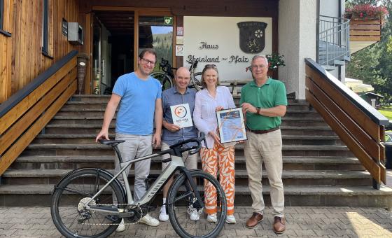 Thomas Kloth, Christof Palm, Carolin von Schlippenbach und Rudolf Storck stehen vor dem Haus Rheinland-Pfalz und halten eine Urkunde in den Händen