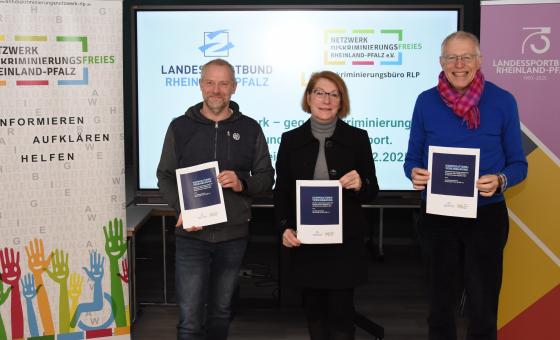 Drei Personen präsentieren Kooperationsvereinbarung