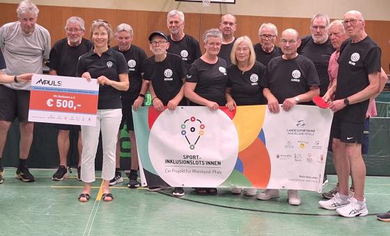 Viele Menschen bei Scheckübergabe in Sporthalle