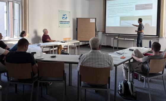 Personen an Tischen in Versammlungsraum