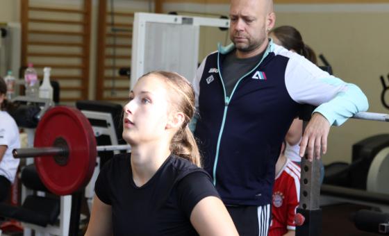 Junge Gewichtheberin mit Trainer